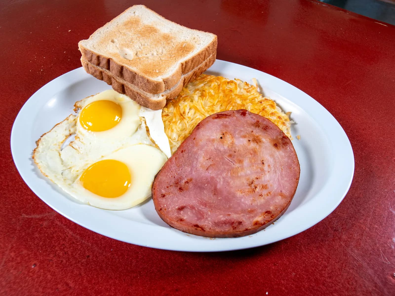Ham and eggs breakfast with toast and hash browns