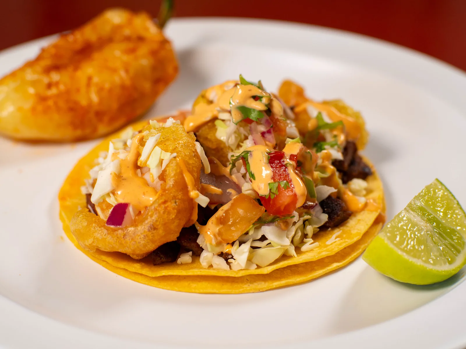 Fish taco with cabbage, crema, salsa and lime